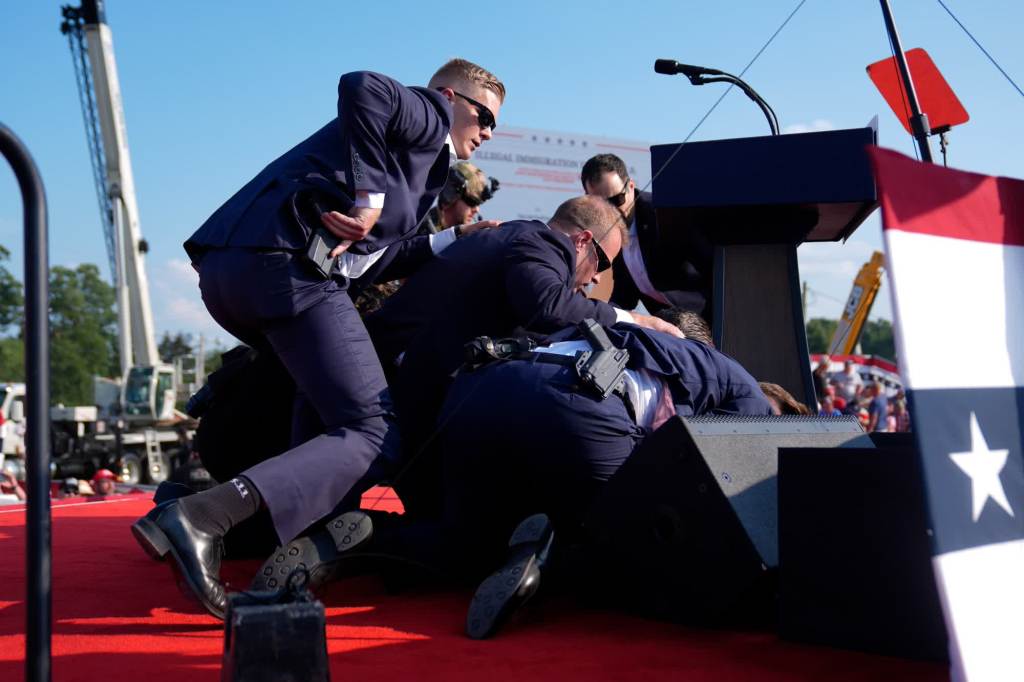 Secret Service agents cover Trump after shots rang out at the rally. (Evan Vucci/AP)