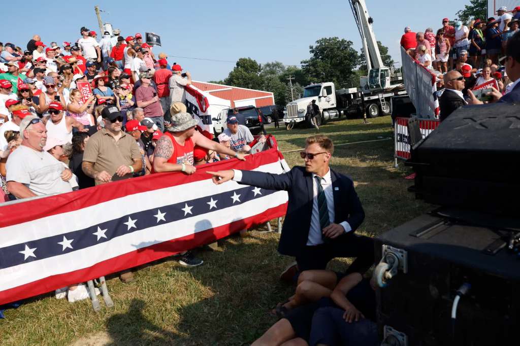 A Trump campaign staffer points as people below him take cover. (Anna Moneymaker/Getty Images)